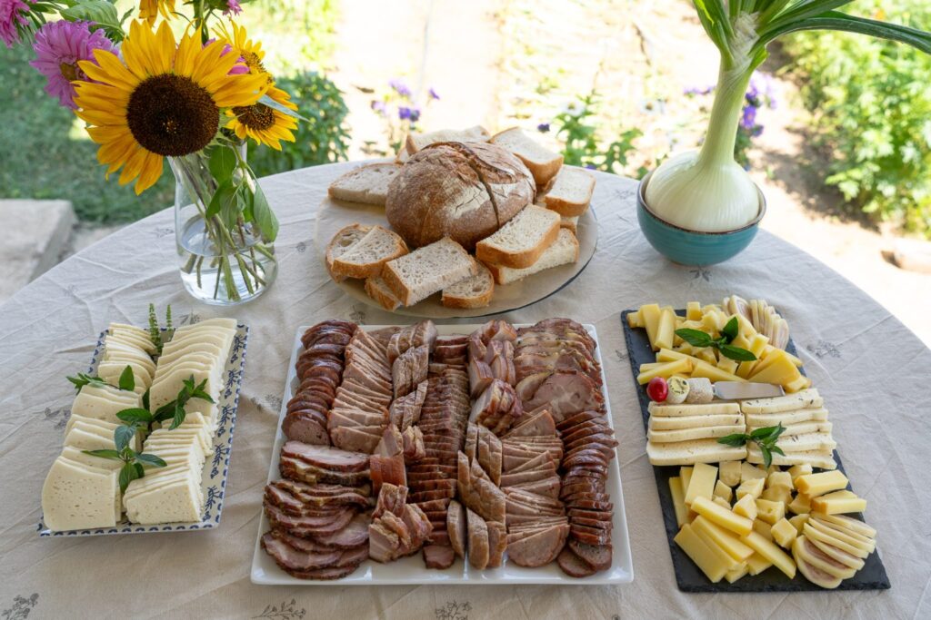 Masa din grădină: pâine, brânzeturi, afumături și floarea-soarelui în vază