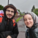Ionuț Teoderașcu și jurnalista Anca Iosif, în pelerine de ploaie și cu rucsacuri, fac un selfie pe un drum ud de sat